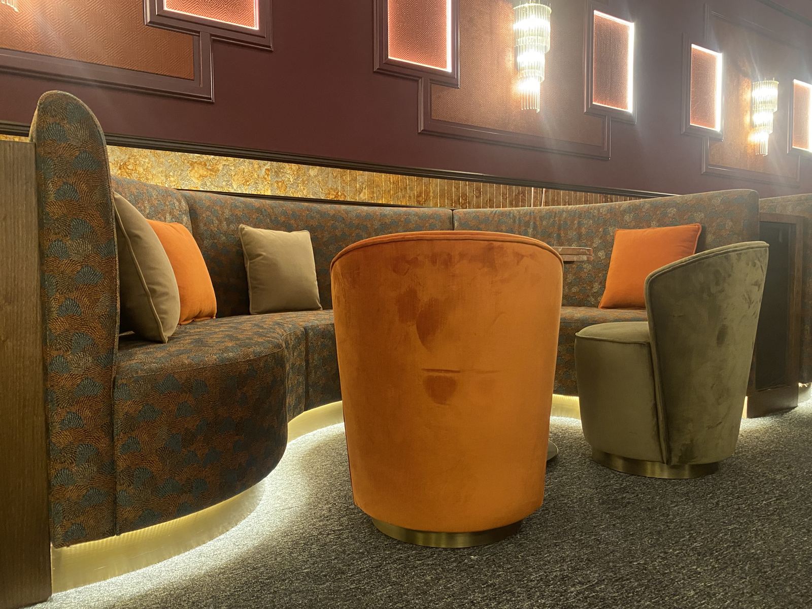 The finished curved banquette lounge with velvet tub chairs and lit wall panels