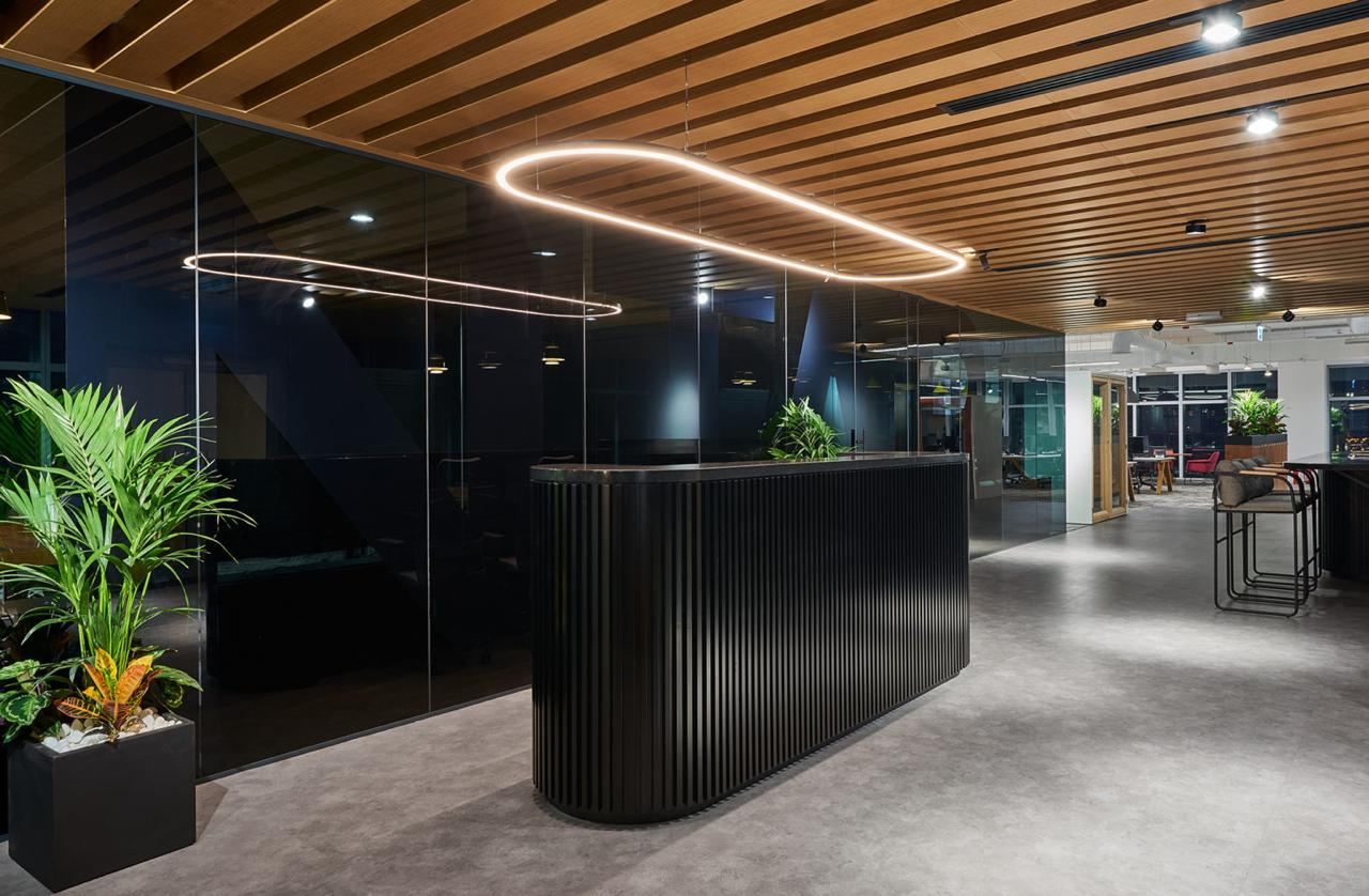 Fluted black reception desk under a slatted timber ceiling
