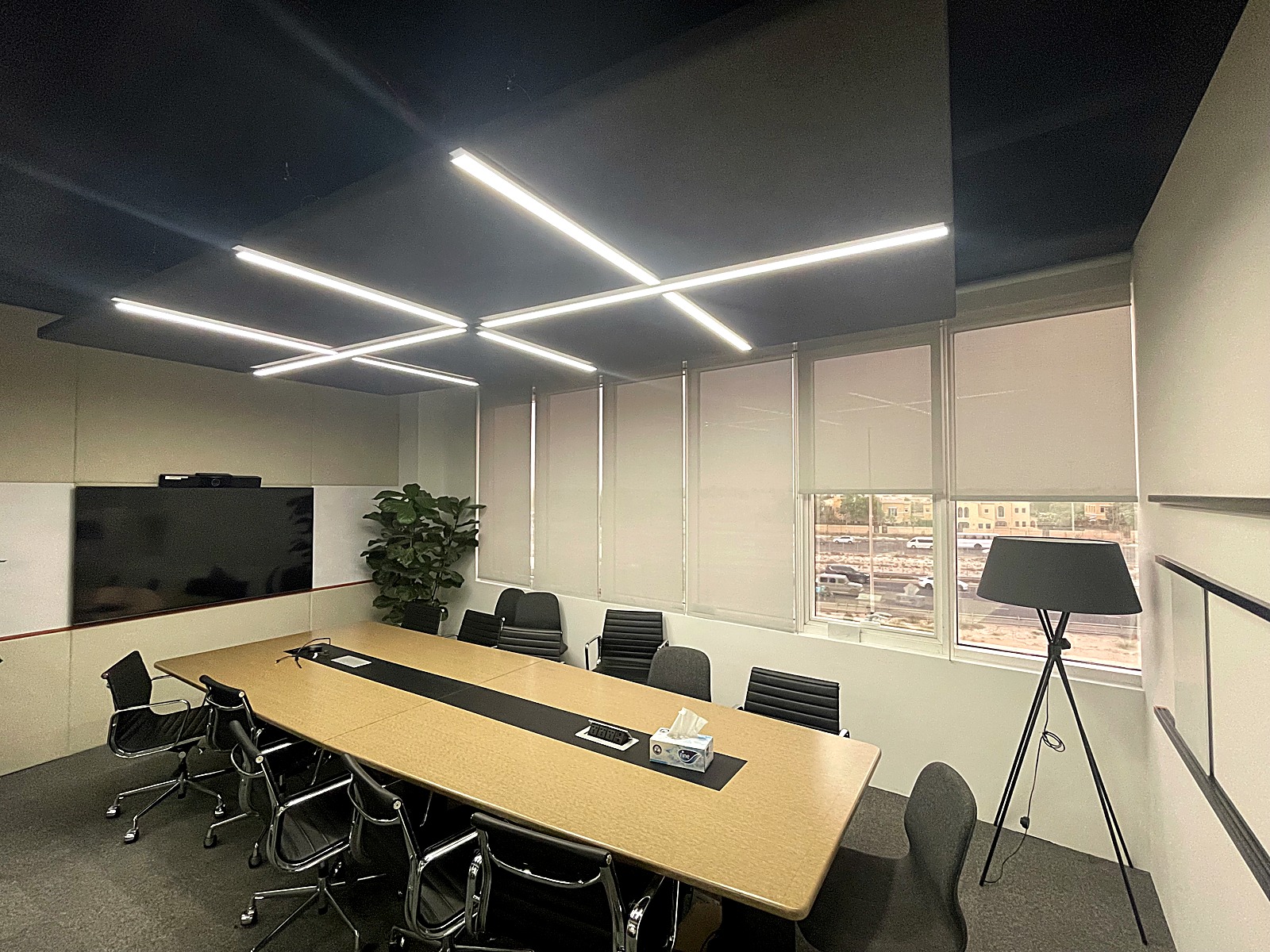 Meeting room with a timber table, black chairs and a wall mounted screen