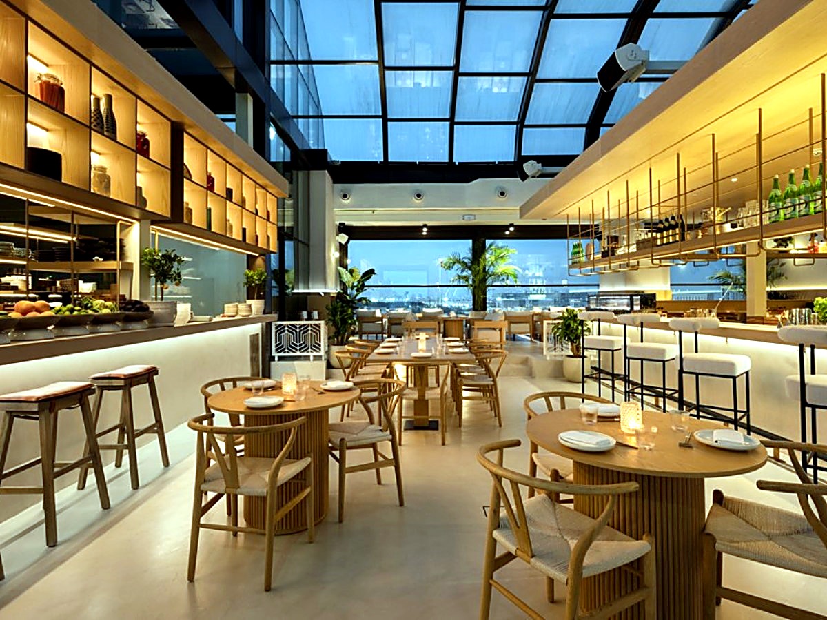 Wide dining room with timber chairs beneath the curved glass roof