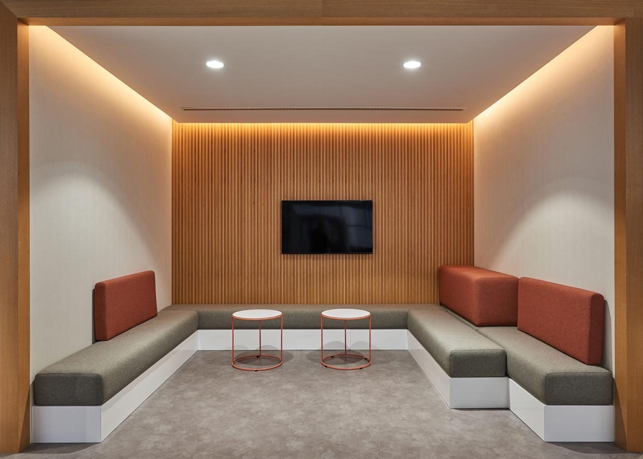 Timber framed breakout booth with grey and rust upholstered benches and slatted wall