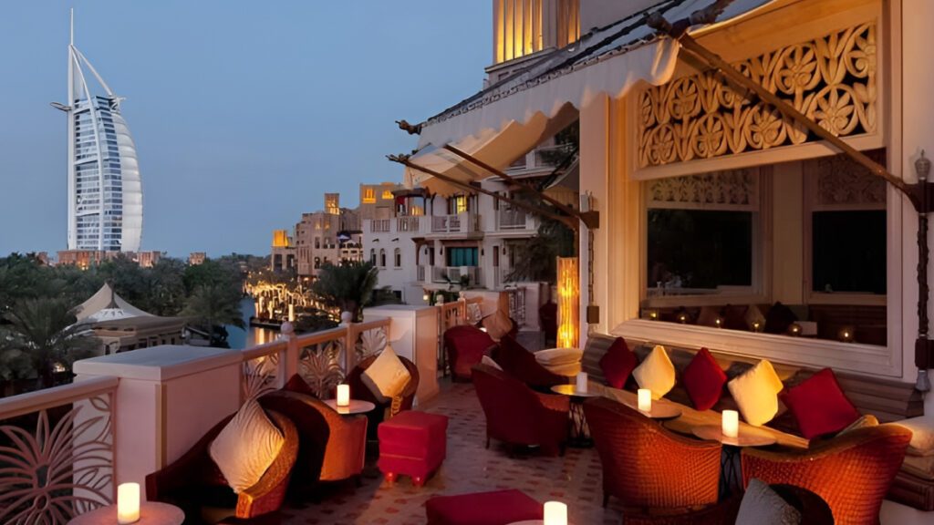 Evening terrace seating with cushions and candles under a carved timber canopy