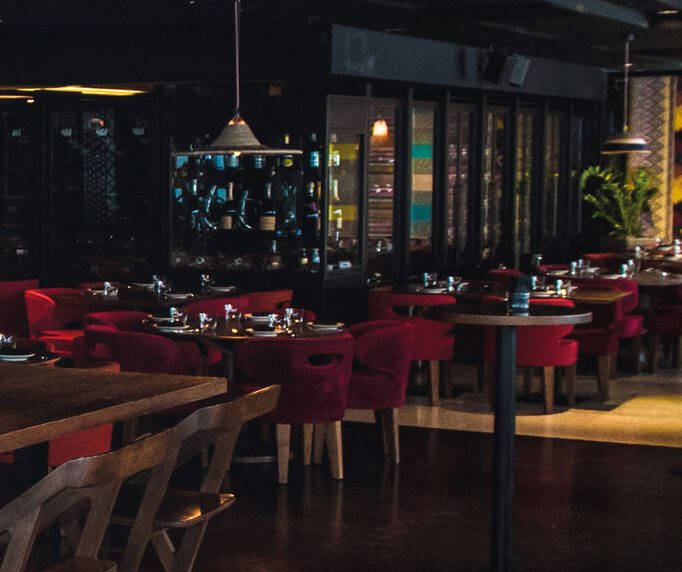 Dining room with red velvet chairs, dark display cabinets and pendant lights