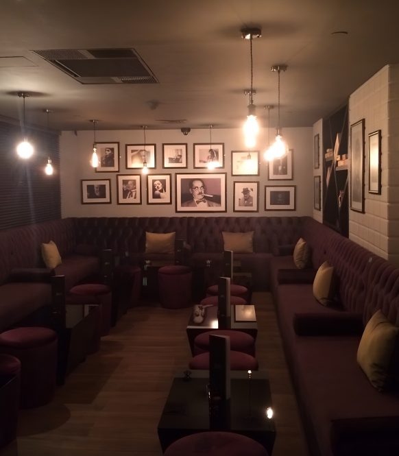 Dim lounge with tufted banquettes and framed black and white photographs