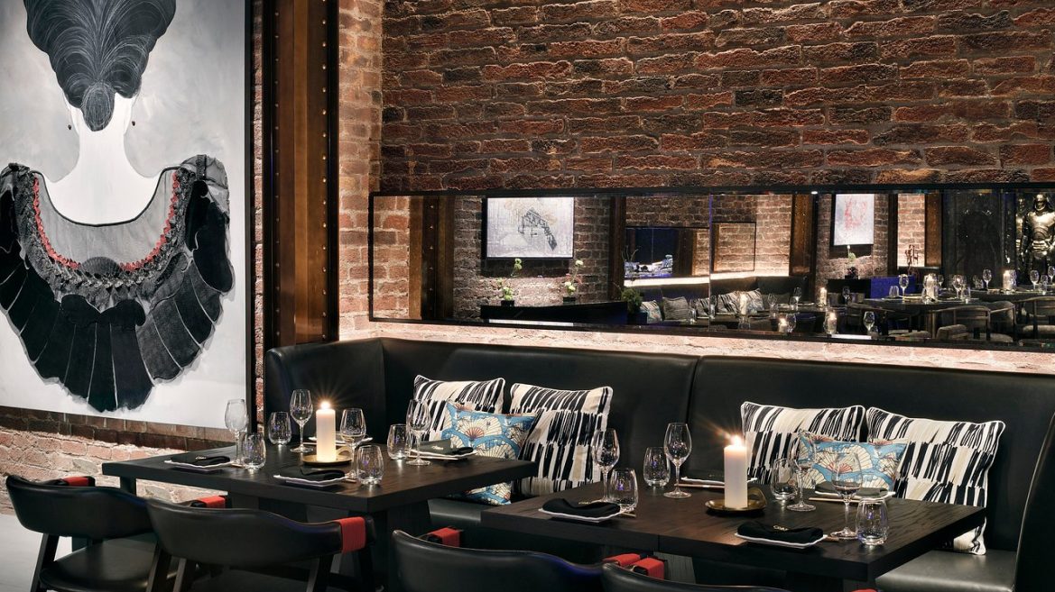 Leather banquette with patterned cushions against an exposed brick wall