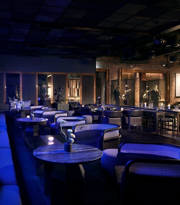Blue lit lounge with round tables and low armchairs