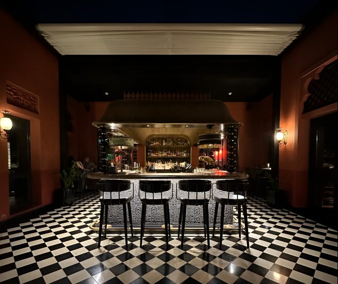 View across a chequered floor to the bar under a lit canopy