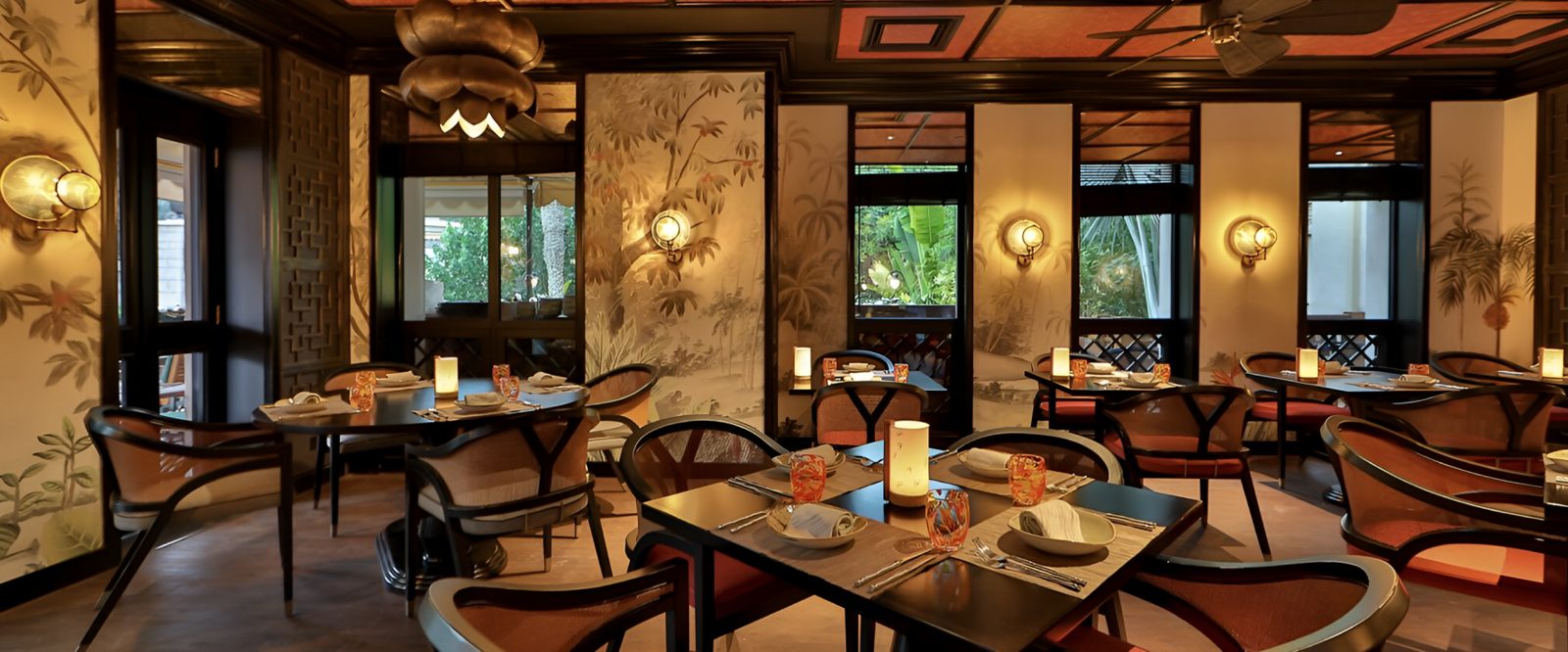 Dining room with timber chairs, botanical wall panels and brass pendant