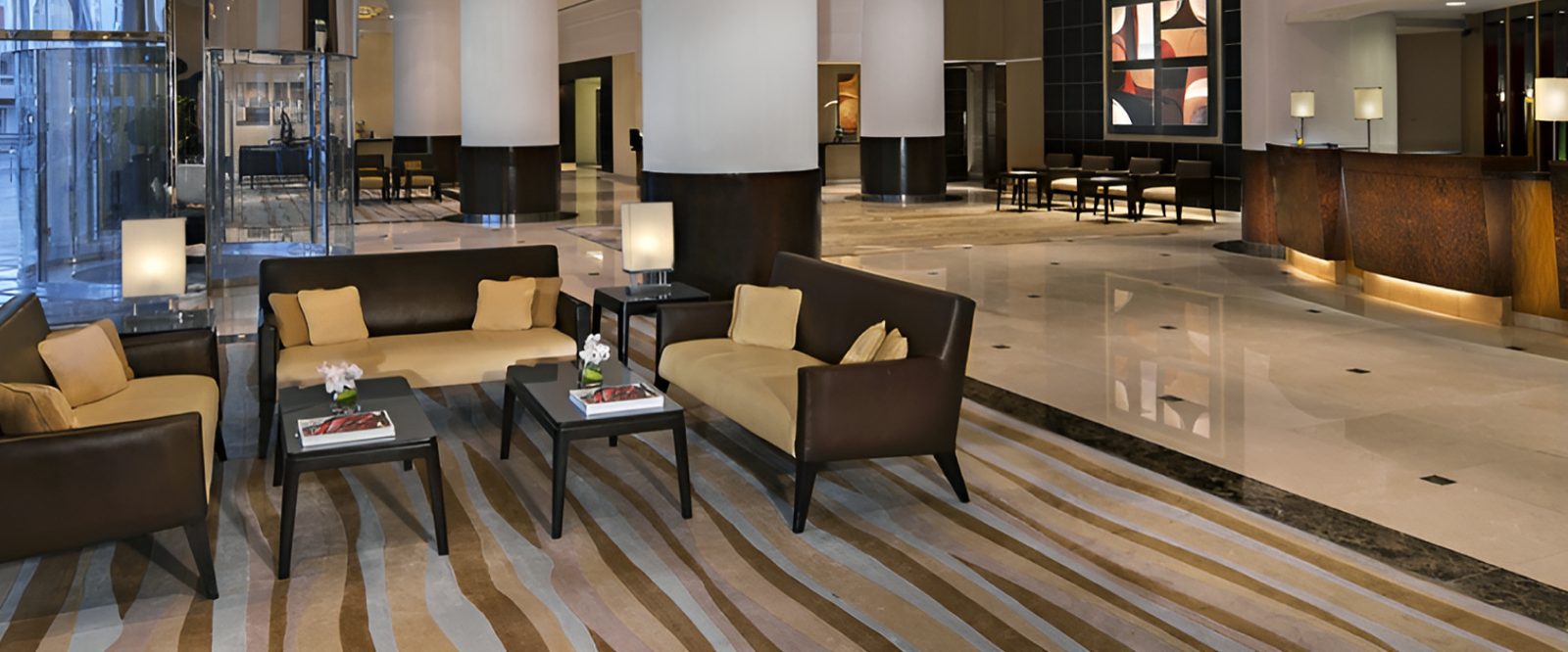 Hotel lobby seating on a marble floor beside the reception desk