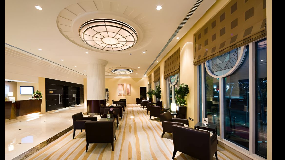 Hotel lounge with dark armchairs, patterned carpet and a round ceiling light