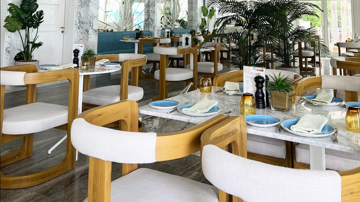 Dining room with teak and white upholstered chairs and marble topped tables