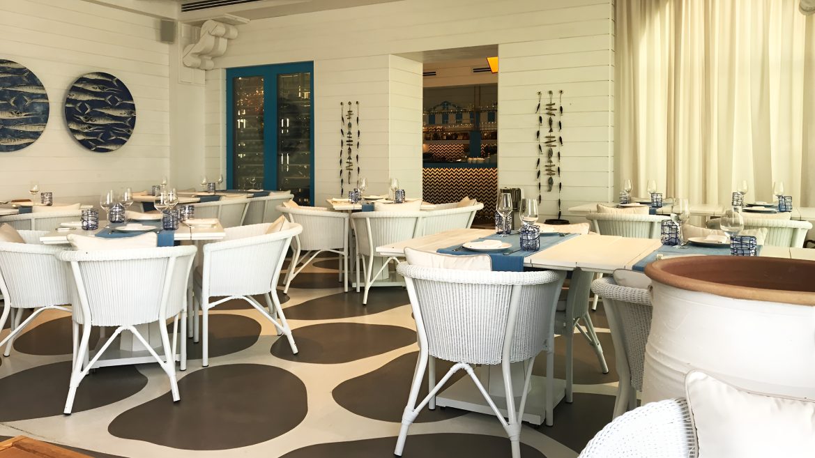Restaurant with white wicker chairs and a patterned floor