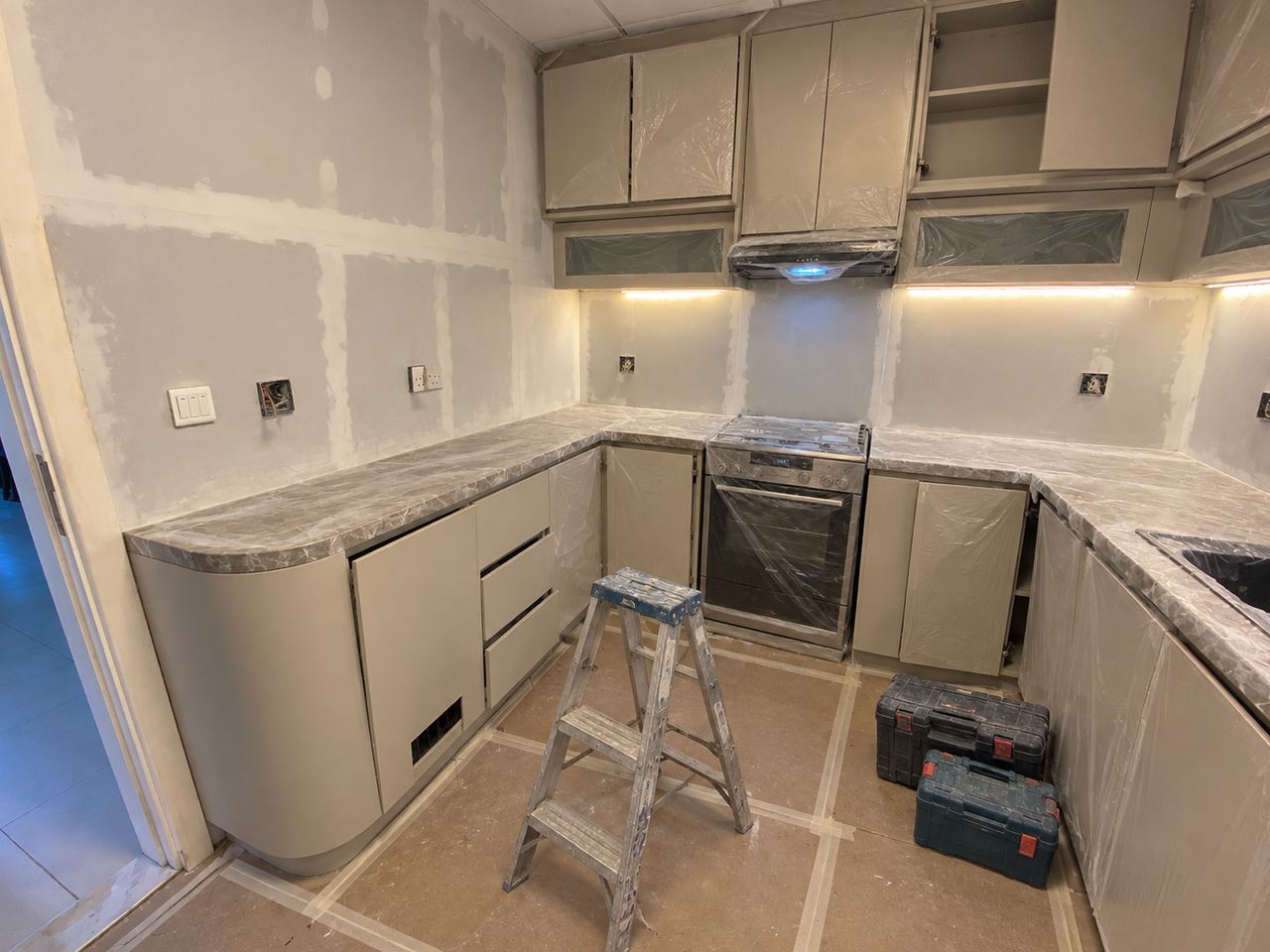 Fitted kitchen with a curved end unit, during fit-out, joinery going in (AI illustration)